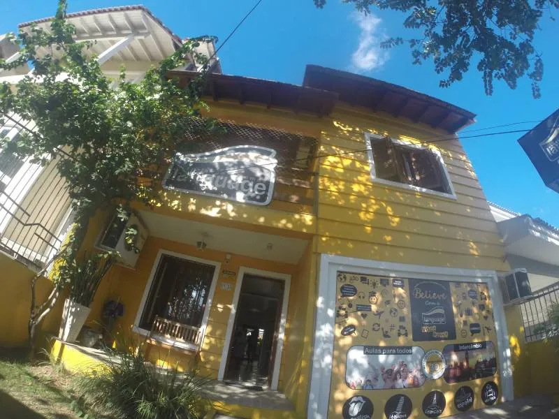 Fachada amarela da Language, uma casa de dois andares com janelas decoradas