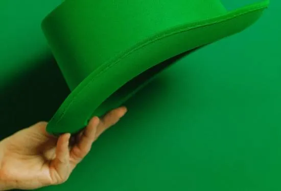 Mão segurando uma cartola verde de St. Patrick’s Day